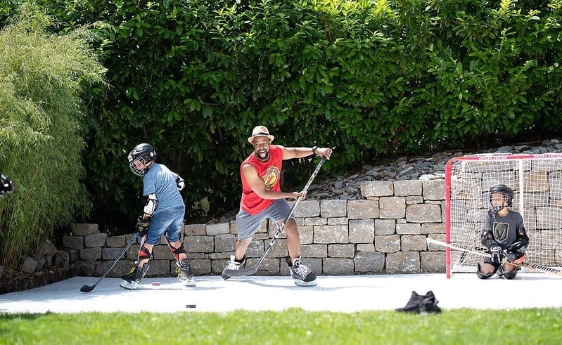 Three people playing ice hockey on synthetic ice